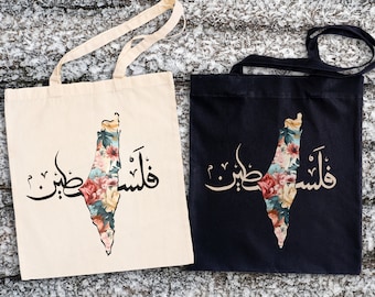 May include: Two tote bags with a floral design of the outline of Israel and the Arabic text "Palestine" in black on a white bag and black on a black bag.