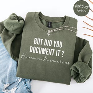 Könnte beinhalten: Ein olivgrüner Sweatshirt mit dem Text "But did you document it? Human Resources" in Weiß.