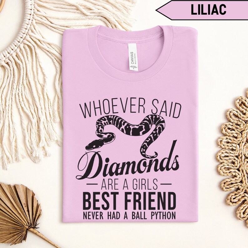 Pu&ograve; includere: Una maglietta lilla con il testo "Whoever said diamonds are a girls best friend never had a ball python" e un'illustrazione in bianco e nero di un serpente.