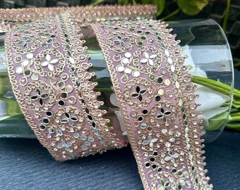May include: Pink and gold trim with mirror and rhinestone embellishments. The trim is made of a sheer fabric and has a delicate, feminine look.
