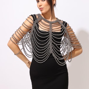Model wearing a Metallic grey shoulder cape with cascading strands and sculptural drape over a black dress. This handmade capelet adds a bold, gothic touch to bridal, evening, or fashion looks.