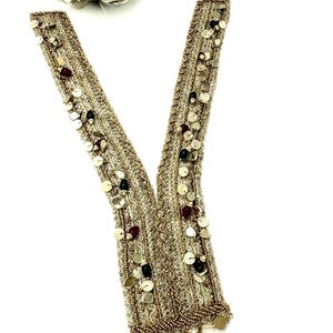 May include: A V-shaped gold embroidered neckline applique featuring intricate metallic thread work, small round gold sequins, and dark red and black beads. The trim is finished with a row of dangling gold sequins along the bottom edge.
