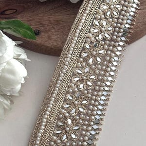 Bundle and strip of gold floral lace with mirror and pearl embellishments, styled for use in bridal, festive, or costume design.