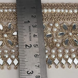 Full view of decorative gold lace trim with beaded pearls and reflective mirror flowers, perfect for sewing and DIY projects.