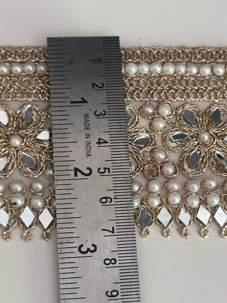 Full view of decorative gold lace trim with beaded pearls and reflective mirror flowers, perfect for sewing and DIY projects.