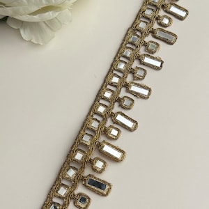 May include: Gold trim with a fringe of rectangular mirror pieces.