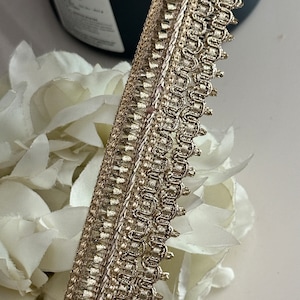 May include: Gold trim with a delicate, intricate design. The trim has a scalloped edge and a subtle shimmer.