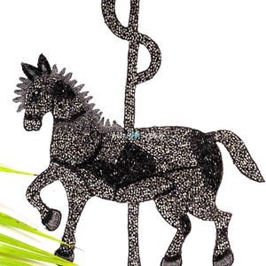 May include: A black and silver beaded carousel horse with a decorative pole. The horse is in a trotting pose, with a detailed mane and tail. The design is on a white background, with a few green leaves in the corner.