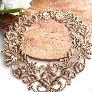 Puede incluir: Borde bordado en oro con un diseño floral y lentejuelas. El borde tiene forma de corazón y es perfecto para añadir un toque de elegancia a cualquier proyecto.