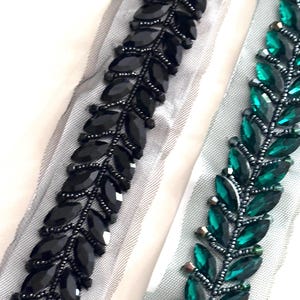 May include: Two beaded trims, one black and one green, with a leaf design. The trim is on a sheer fabric background.