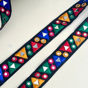 Può includere: Finitura nera con triangoli ricamati colorati e accenti a specchio rotondi.