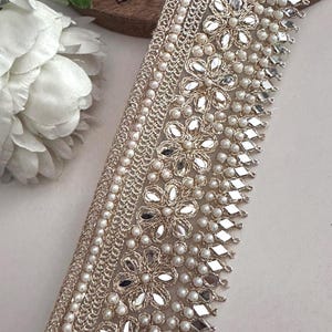 Bundle and strip of gold floral lace with mirror and pearl embellishments, styled for use in bridal, festive, or costume design.