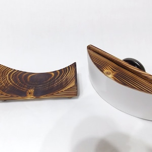 K&ouml;nnte beinhalten: Zwei gebogene Holztabletts mit einer gebrannten Holzoptik. Das Tablett links ist kleiner und hat innen eine nat&uuml;rliche Holzfarbe. Das Tablett rechts ist gr&ouml;&szlig;er und hat innen eine wei&szlig;e Oberfl&auml;che.