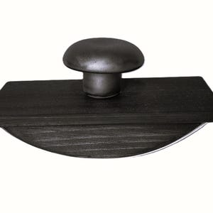 Peut inclure: Un buvard d'encre gris foncé avec une base arrondie et une poignée en forme de champignon. Le buvard est en bois et a une finition lisse et polie. La poignée est centrée sur le dessus du buvard rectangulaire.