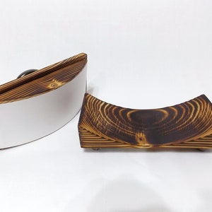 K&ouml;nnte beinhalten: Zwei Holz-Untersetzer, einer mit einem wei&szlig;en Einsatz und der andere mit einer dunkelbraunen Holzmaserung. Beide Untersetzer sind gebogen und haben ein einzigartiges Design.