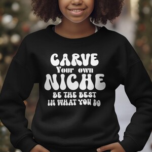 May include: Black sweatshirt with white text that reads "Carve Your Own Niche Be The Best In What You Do" in a retro font.