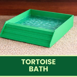 Pode incluir: Um banho de tartaruga verde brilhante com um efeito de água texturizada no interior. O banho tem um lado inclinado com ranhuras horizontais. As palavras "TORTOISE BATH" são exibidas em texto branco em uma faixa verde abaixo.