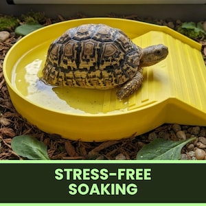 May include: A yellow plastic soaking dish with an integrated ramp, featuring a patterned tortoise partially submerged in water. The dish includes a textured ramp for easy access. The text STRESS-FREE SOAKING is displayed in a green banner at the bottom.