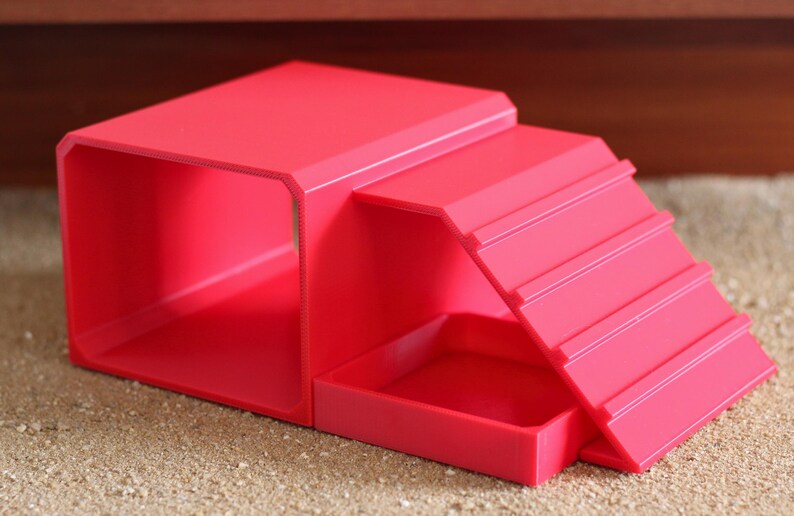 May include: A bright pink pet accessory featuring a hollow rectangular tunnel section connected to a ramp with horizontal ridges and a small square platform base. The structure is made of smooth, solid-colored plastic with a uniform matte finish.