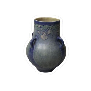 May include: A blue ceramic vase with two handles and a wide body. The vase features a floral design around the rim and a vertical stripe down the front. The vase has a matte finish.