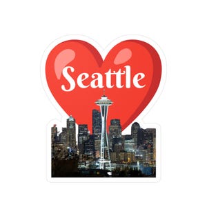 May include: A sticker featuring the Seattle skyline with the Space Needle in the center. The skyline is set against a red heart shape with the word "Seattle" in white script.