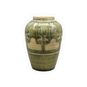 May include: A decorative ceramic vase with a light green and cream color scheme. The vase features a repeating tree-like pattern around the top and a horizontal band near the base. The design is reminiscent of Art Deco style.