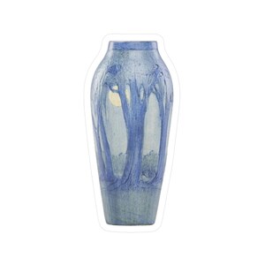 May include: A blue ceramic vase with a tall, slender shape. The vase features a design of stylized trees in shades of blue and white, with a light-coloured area suggesting a moon or light source. The vase has a textured surface.