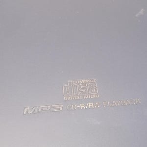 Peut inclure: Un lecteur CD gris avec le texte "COMPACT DISC DIGITAL AUDIO" et "MP3 CD-R/RW PLAYBACK" imprim&eacute; sur la surface. Le lecteur a une forme rectangulaire.