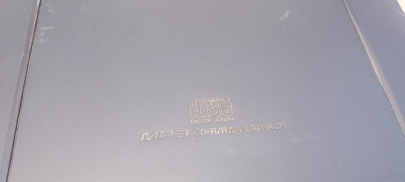 Peut inclure: Un lecteur CD gris avec le texte "COMPACT DISC DIGITAL AUDIO" et "MP3 CD-R/RW PLAYBACK" imprim&eacute; sur la surface. Le lecteur a une forme rectangulaire.