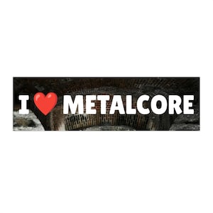 Puede incluir: Una pegatina rectangular con las palabras "I ❤️ METALCORE" en letras blancas y en negrita. El corazón es rojo. El fondo es una imagen borrosa de un arco de ladrillo.