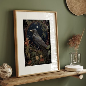 May include: Framed art print featuring a black crow perched on a branch in a lush, green forest setting. The crow is surrounded by flowers and leaves, and the background is a dark, moody sky. The print is framed in a simple, wooden frame.