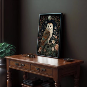 May include: Framed art print featuring a detailed illustration of a barn owl perched amidst flowers and foliage. The owl has white and brown feathers, set against a dark background with floral accents. The artwork is displayed on a wooden table.