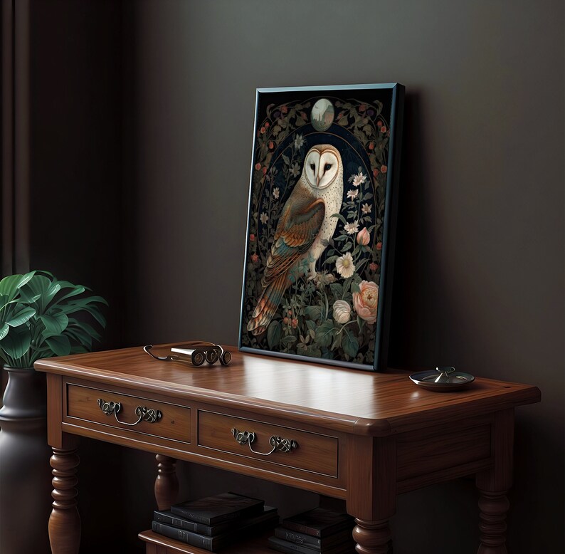 May include: Framed art print featuring a detailed illustration of a barn owl perched amidst flowers and foliage. The owl has white and brown feathers, set against a dark background with floral accents. The artwork is displayed on a wooden table.