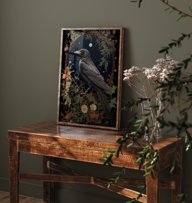 May include: A framed print of a black raven perched on a branch in a forest setting. The raven is surrounded by flowers and leaves, and the background is a dark blue sky with stars. The print is in a gold frame.