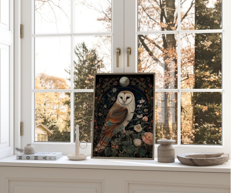 May include: Framed art print featuring a detailed illustration of a barn owl with brown, white, and orange feathers, perched amidst floral elements. The artwork has a dark background with a moon and is displayed on a windowsill.