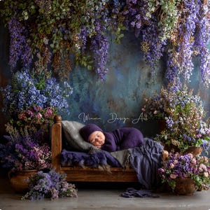 May include: A newborn baby in a purple outfit and hat sleeps peacefully on a small wooden bed. The bed is draped with a gray pillow and a purple blanket. The background features a floral arrangement with purple and blue flowers.