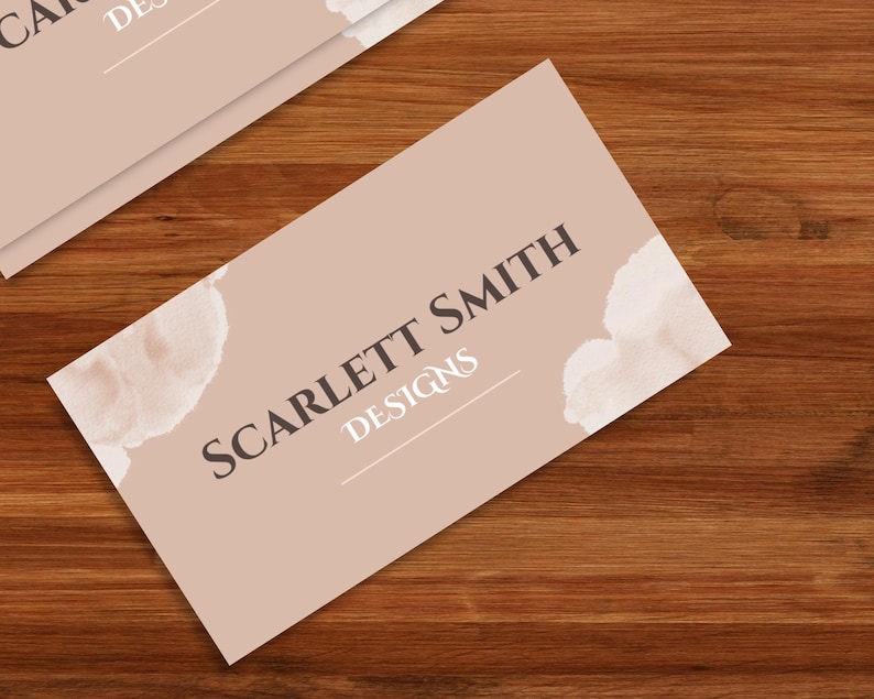 Pode incluir: Um cart&atilde;o de visita de cor castanho claro com o texto "SCARLETT SMITH DESIGNS" em letras castanho escuras. O cart&atilde;o tem um design de aquarela com formas abstratas brancas e castanhas claras.