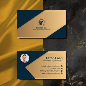Pode incluir: Um cart&atilde;o de visita com um design dourado e azul. O cart&atilde;o apresenta o nome "Aaron Loeb" e o t&iacute;tulo "Consultor de Neg&oacute;cios". O cart&atilde;o tamb&eacute;m inclui informa&ccedil;&otilde;es de contato, incluindo um endere&ccedil;o de e-mail, um n&uacute;mero de telefone e um endere&ccedil;o de site.