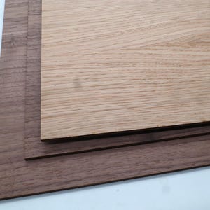 May include: Three pieces of wood, one light brown and two dark brown, stacked on top of each other.