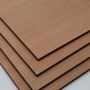 K&ouml;nnte beinhalten: Vier rechteckige Holzplatten in einem r&ouml;tlich-braunen Farbton sind diagonal gestapelt. Die Holzmaserung ist sichtbar und verl&auml;uft horizontal &uuml;ber jede Platte. Die Kanten der Platten sind dunkler braun und bilden einen definierten Rand.