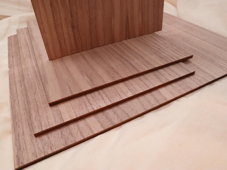 May include: Four pieces of wood veneer stacked on top of each other. The wood has a light brown color and a wood grain pattern.