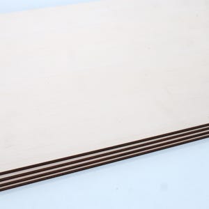 May include: Stack of four unfinished wood sheets, each with a smooth, light brown surface.