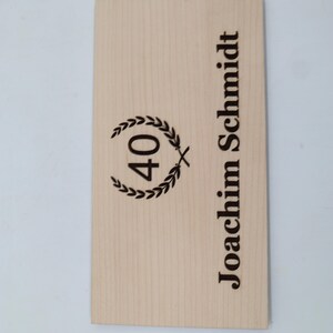 May include: A wooden plaque with the text "Joachim Schmidt" and a laurel wreath with the number "40" inside.