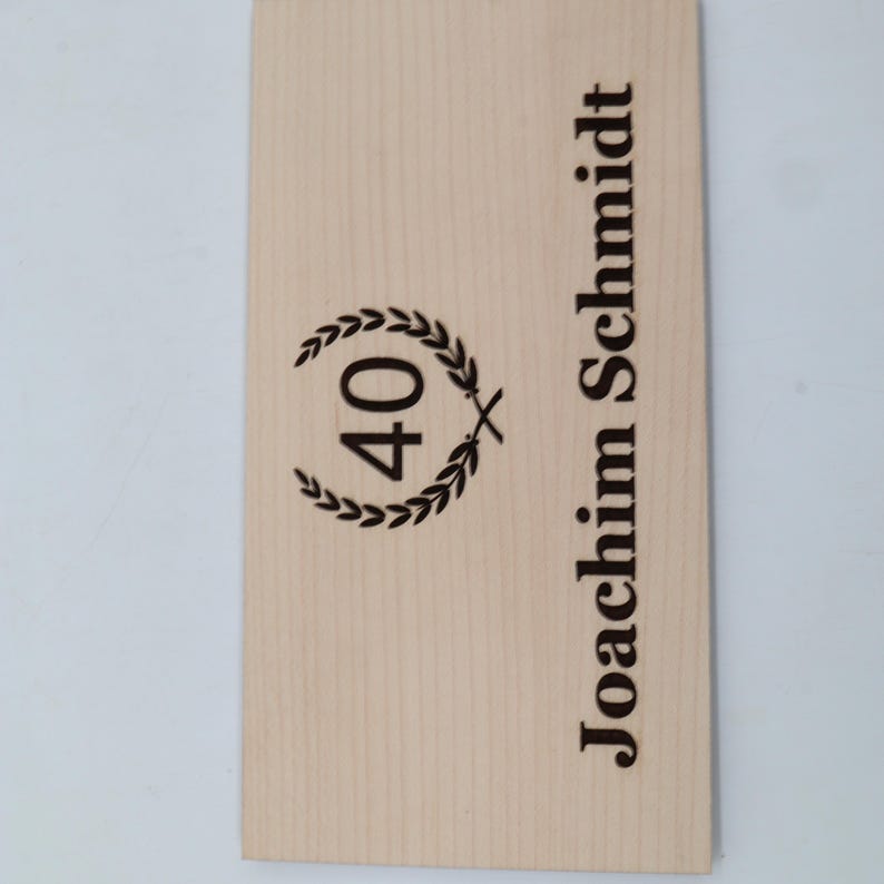 May include: A wooden plaque with the text "Joachim Schmidt" and a laurel wreath with the number "40" inside.