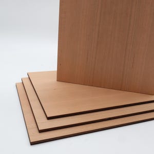 K&ouml;nnte beinhalten: Ein Stapel aus vier rechteckigen Holzplatten. Das Holz hat einen r&ouml;tlich-braunen Farbton mit sichtbaren Maserungsmustern. Die Platten sind in Schichten angeordnet, wobei eine aufrecht steht und die anderen flach liegen.