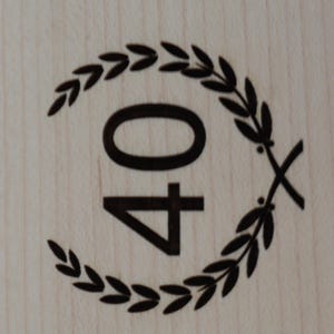 May include: A black and white image of the number 40 surrounded by a wreath of leaves. The number 40 is centred in the image and the wreath of leaves is around the outside of the number.