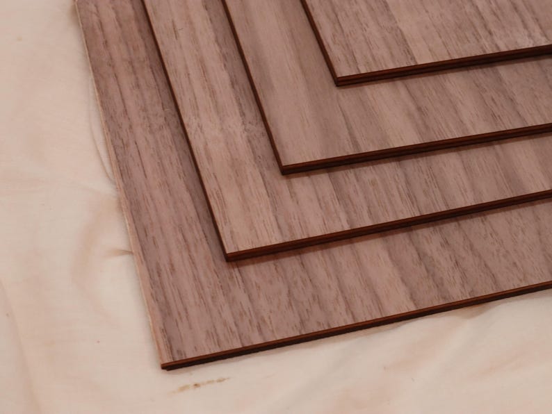 May include: Four pieces of wood veneer, each with a different wood grain pattern, are stacked on top of each other. The wood is a light brown color with a reddish hue.