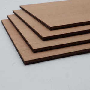 K&ouml;nnte beinhalten: Vier rechteckige Holzplatten &uuml;bereinander gestapelt. Die Platten haben eine hellbraune Holzmaserungsoberfl&auml;che mit dunkelbraunen Kanten. Die Platten sind diagonal angeordnet und zeigen ihre geschichtete Struktur.