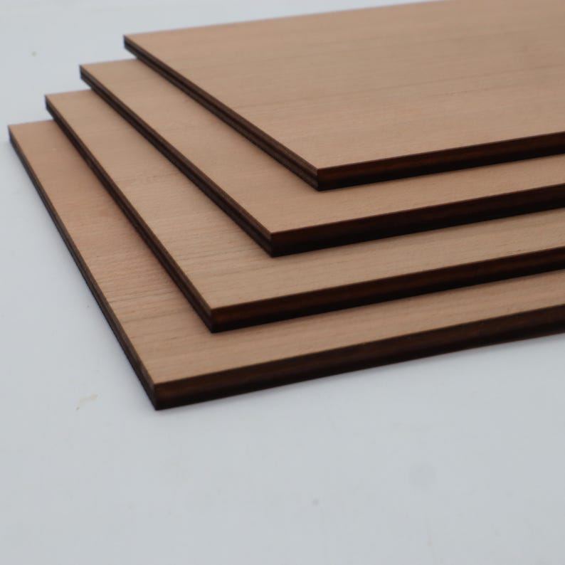 K&ouml;nnte beinhalten: Vier rechteckige Holzplatten &uuml;bereinander gestapelt. Die Platten haben eine hellbraune Holzmaserungsoberfl&auml;che mit dunkelbraunen Kanten. Die Platten sind diagonal angeordnet und zeigen ihre geschichtete Struktur.