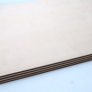 May include: A stack of four sheets of light brown plywood with a smooth surface.